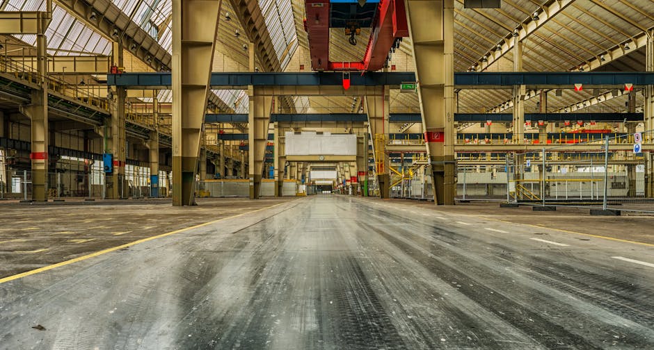 Wide view of an empty industrial warehouse with visible cranes and metal structures.