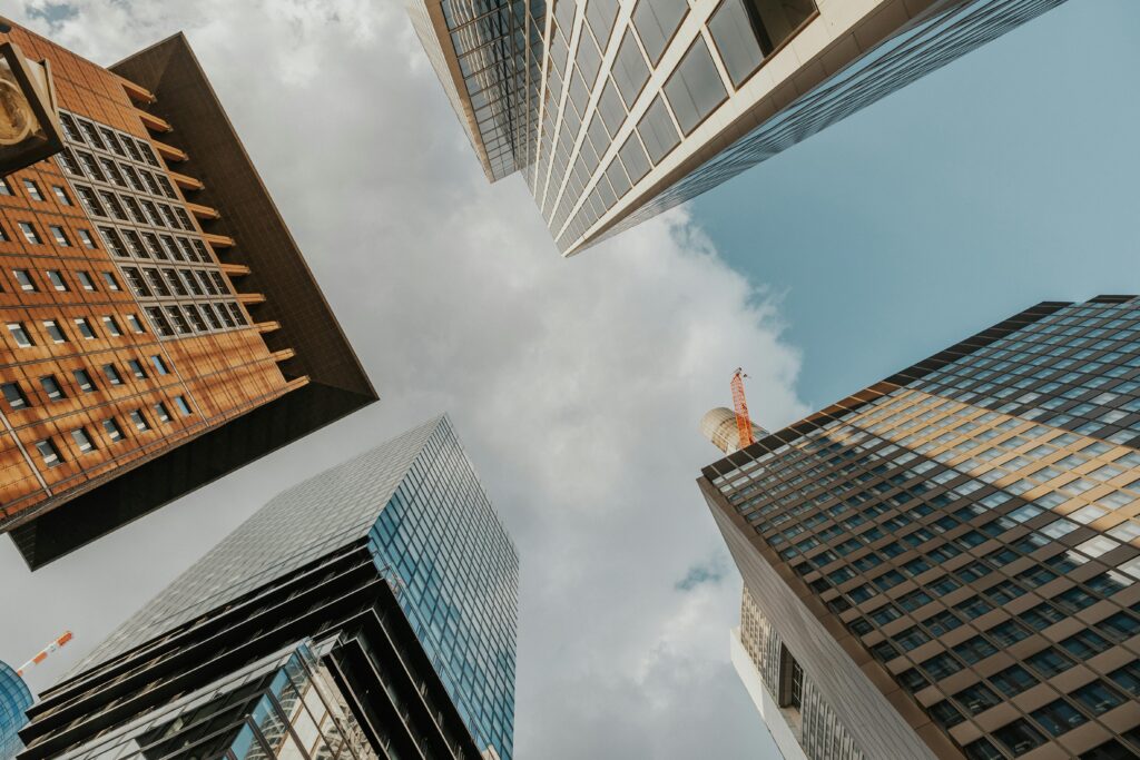 Low angle shot of modern skyscrapers against a blue sky with clouds, showing dynamic urban architecture.