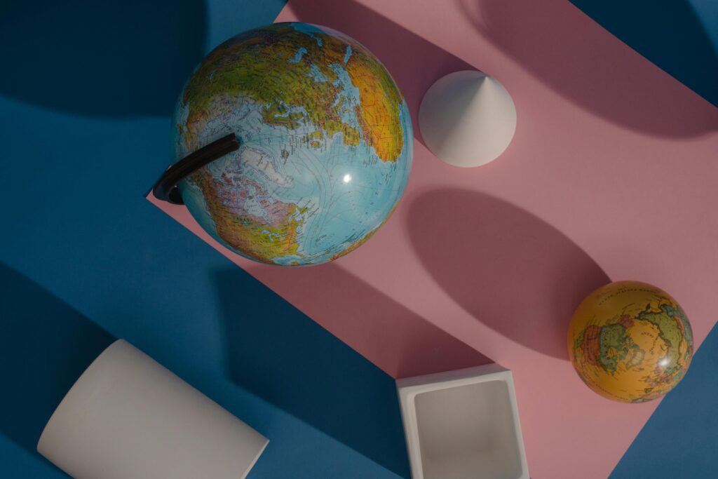Artistic flat lay of globes and geometric shapes on colorful background.
